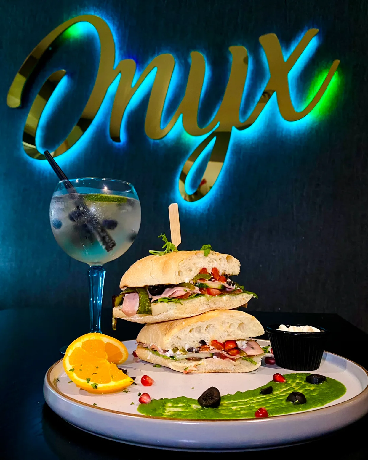 Sandwich with a cocktail in front of the Onyx sign