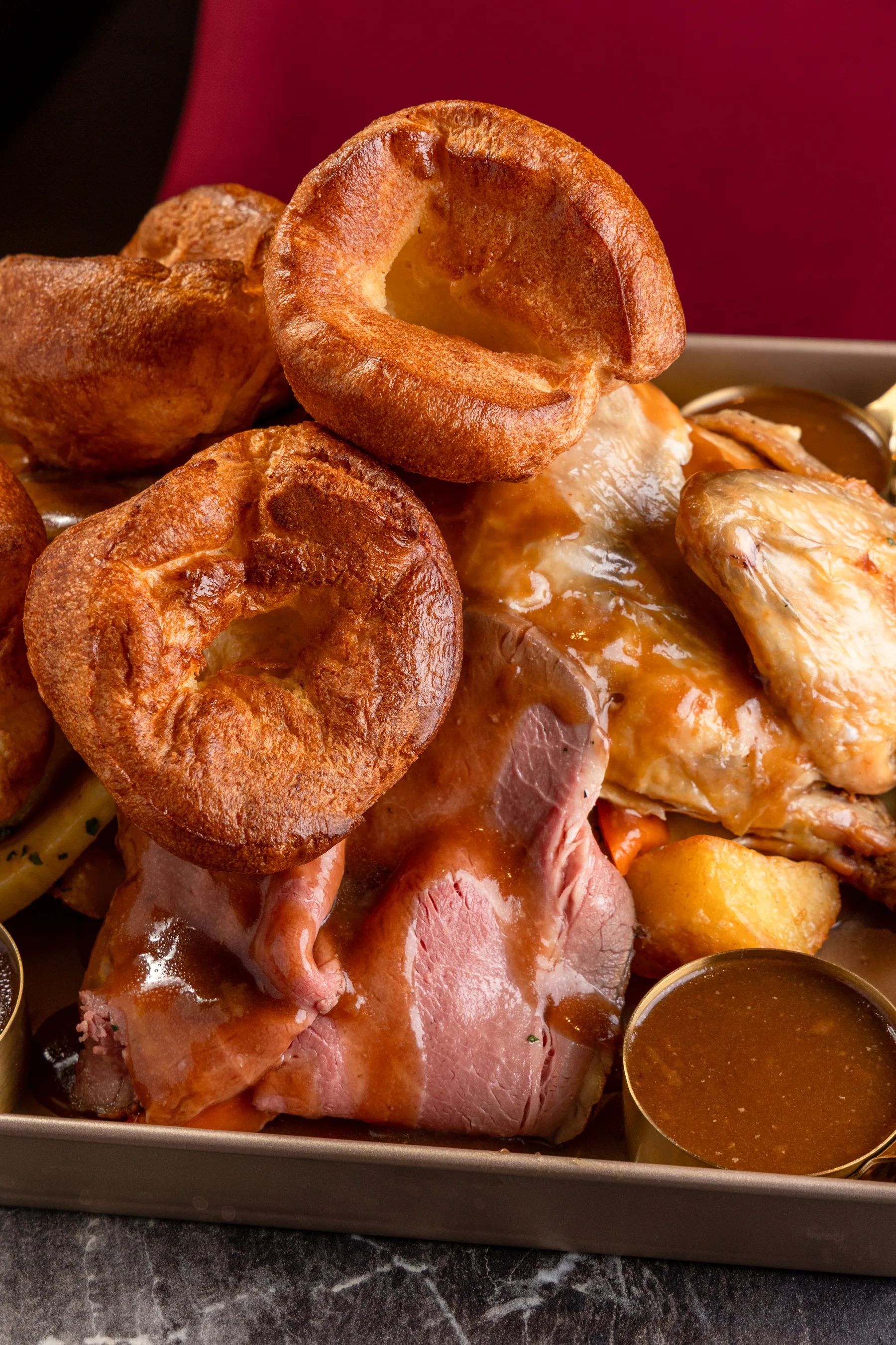 Close-up Sunday roast sharing platter with Yorkshire puddings and vegetables